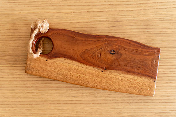 istock Handmade wooden serving board with natural wood grain and a rope handle, placed on a light wooden surface. 2225223349