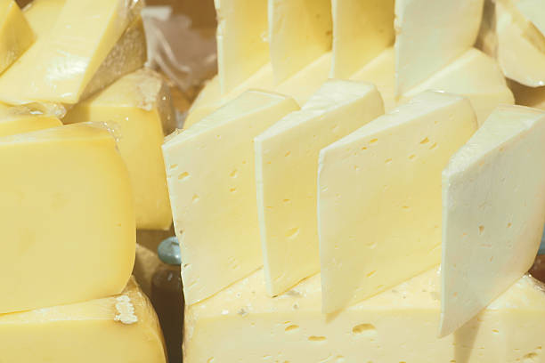 A yellow cheese is sitting in a paper wrapper, popular soft french cheeses