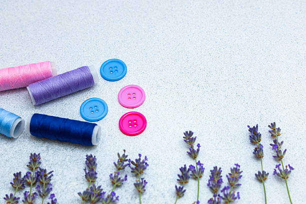 istock Colorful sewing threads and buttons arranged with fresh lavender on a light surface 2225226927