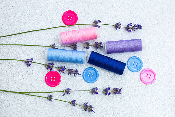 istock Colorful spools of thread and buttons arranged with lavender sprigs on a light surface 2225226930