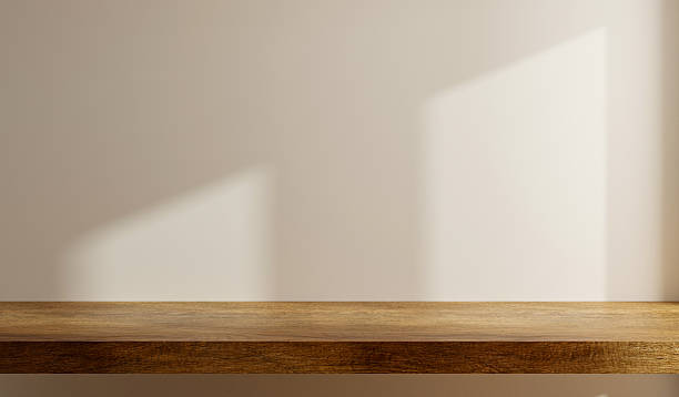 Minimalist interior featuring a clean wooden shelf against a soft beige wall, illuminated by natural light- 3D rendering