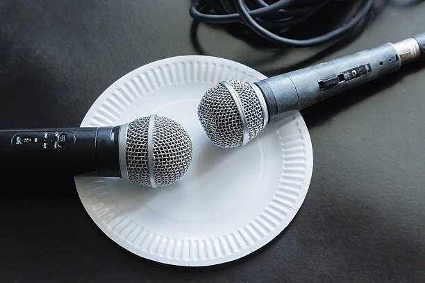 istock Two old worn microphones lie on a disposable white plate close-up on a black background, political debates or talk shows, sensational journalism, commissioned interview, fake news. 2225227966