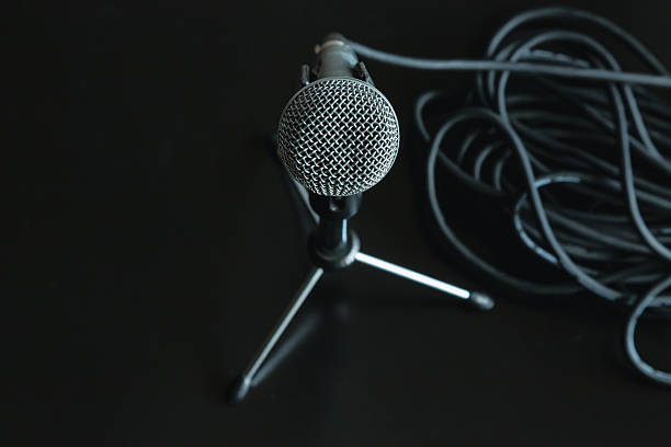 istock A microphone stands on a special microphone stand on a black table surface next to a coiled black audio cable close-up, freedom of speech, public speaking and interview, podcast and live broadcast. 2225227971