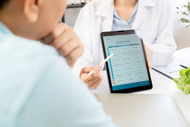 istock Asian nutritionist using tablet to explaining personalized meal plan with AI to patient during healthcare consultation, healthy lifestyle, woman dietitian showing nutrition plan with AI on tablet. 2225228012