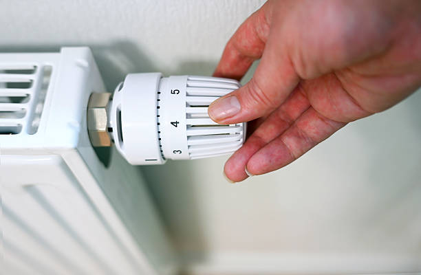 istock Person is adjusting temperature on radiator 2225230070