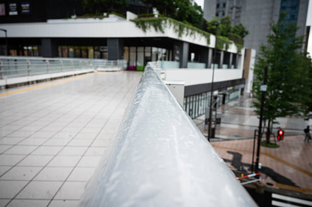 The handrail of the pedestrian bridge is wet with raindrops and no one touches it.