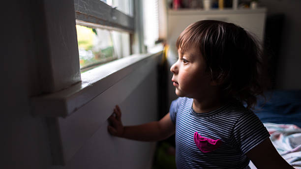istock Curious Little Girl Looking Out the Window 2225232614
