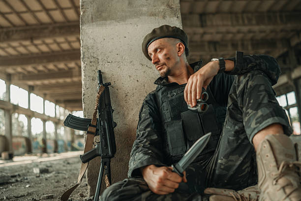 A fatigued soldier takes a break in a dilapidated facility, armed and contemplative. Capturing themes of war, fatigue, and solitude, this image conveys the solemnity and strength of military life.