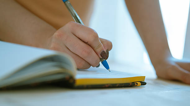 istock Female hand writing in notebook, close up 2225237154