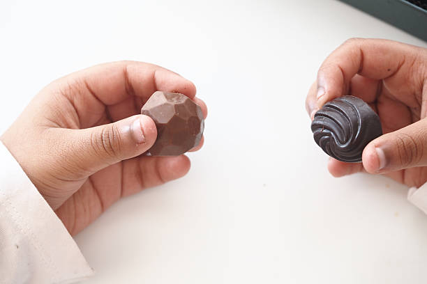 istock Child Hands holding two different chocolate shapes indoors 2225237988