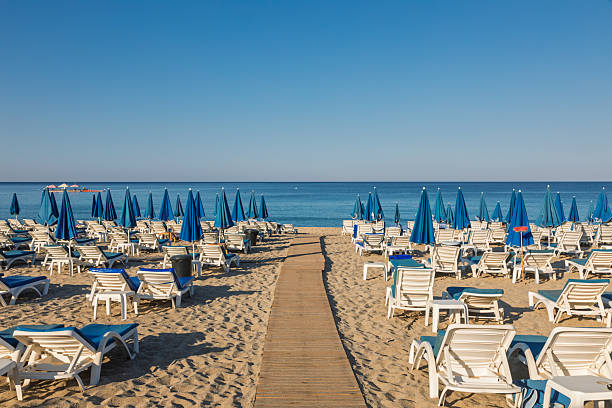 istock Early morning empty beach with loungers and blue umbrellas 2225241508