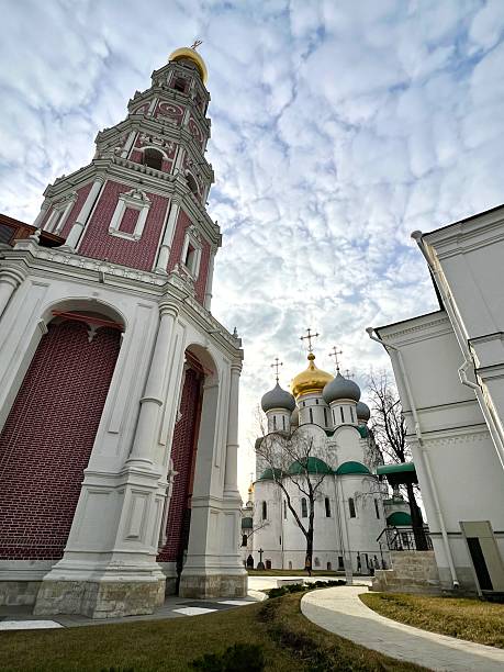 A white church in Kremlin in Moscow Russia with three domes and three crosses on top. The church is surrounded by trees