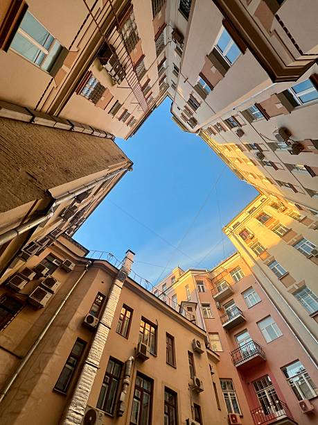 Looking up from within a courtyard surrounded by tall, closely built residential buildings, commonly known as a \