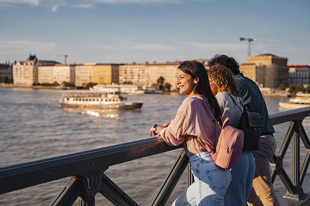 Three young tourists admiring Budapest cityscape from a bridge at sunset