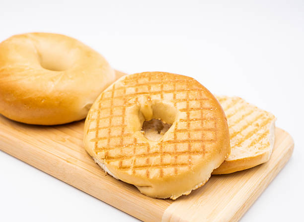 Plain Toasted Bagel on Wooden Board isolated on white background side view of Classic Breakfast