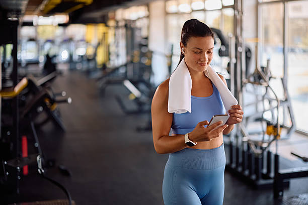 istock Happy athletic woman texting on cell phone while exercising in a gym. 2225261602