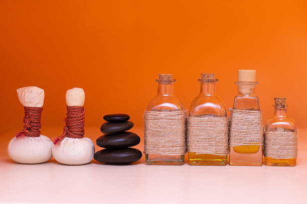 beautiful bottles with massage oil on orange background