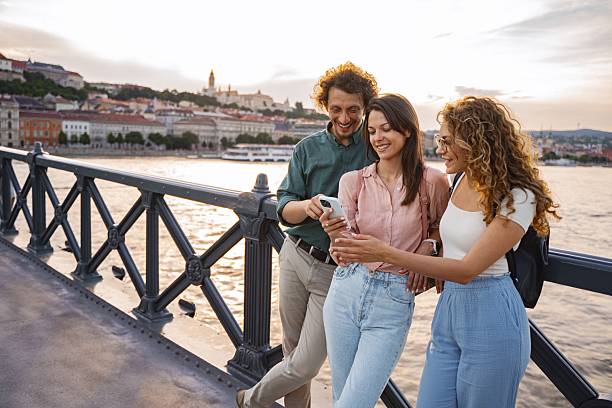 istock Tourists using smartphone on bridge in Budapest at sunset with Buda Castle in background 2225262690