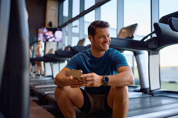 istock Happy athlete using app on mobile phone while working out in health club. 2225263368