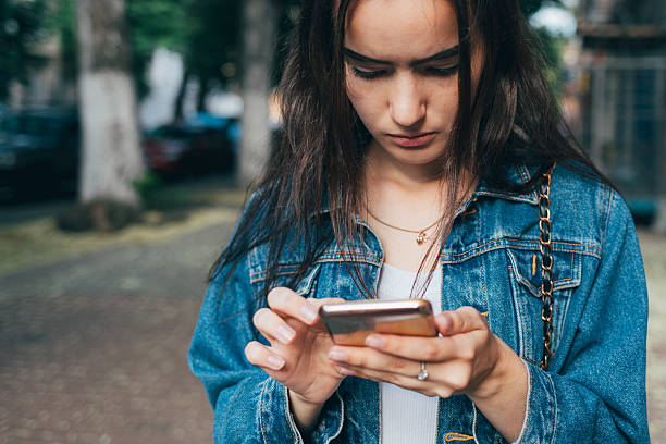 istock Woman in a blue jacket is looking at her cell phone 2225267121