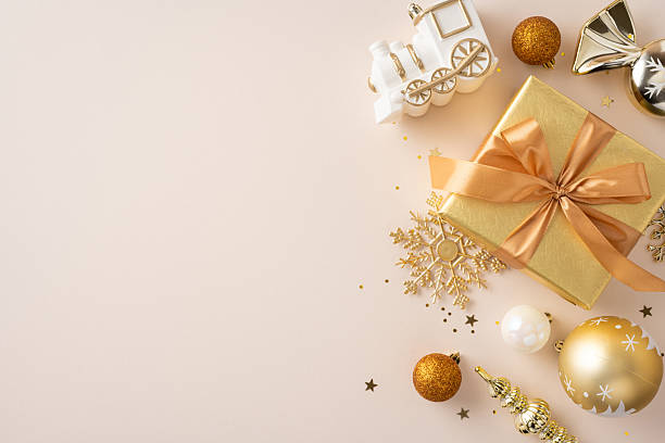 Christmas themed flatlay with gold gift box, ornaments, and decorations on a beige backdrop