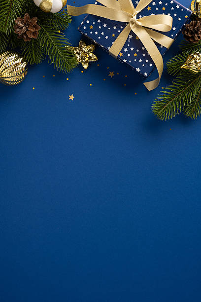 istock Festive Christmas decorations with a wrapped gift box and ornaments on a vertical blue surface 2225270796