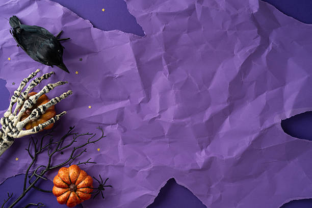 istock A Halloween-themed composition showing spooky elements, including a skeleton hand, crow, and pumpkin, on a purple textured background 2225270819