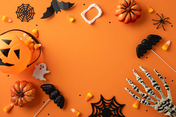 istock Decorative Halloween orange backdrop featuring pumpkins, bats, a skeleton hand, and candy corn 2225270831