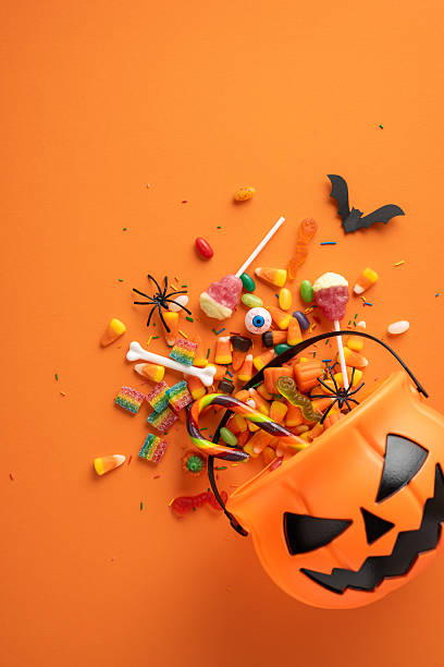 istock Halloween vertical candy and decorations scattered with a jack-o'-lantern bucket on orange. Spooky and festive atmosphere ideal for seasonal celebrations 2225270849