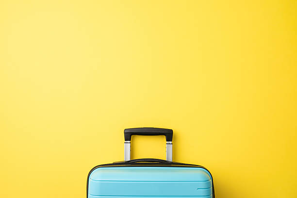 istock A stylish light blue suitcase shown in front of an intense yellow-colored wall surface 2225270857