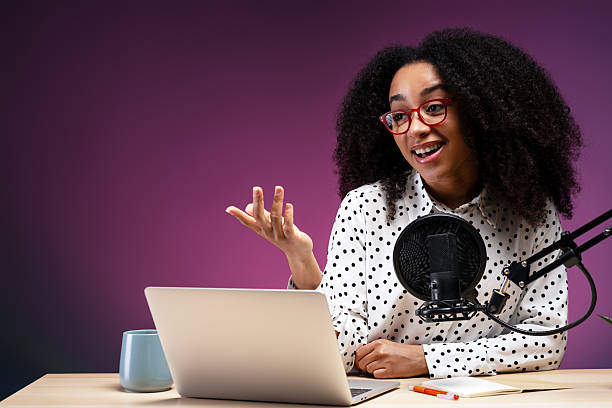 Young woman recording a podcast using laptop and microphone