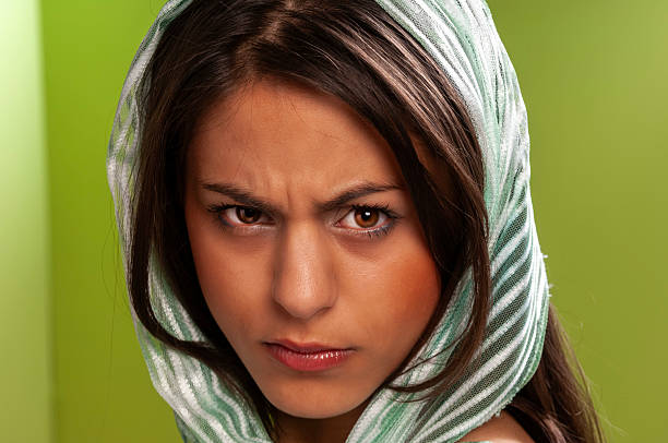 close up of a young woman wearing a veil looking angry in the camera on green background