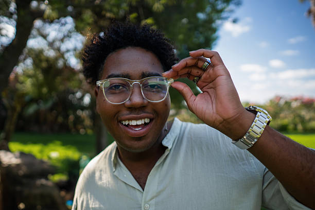istock Young man smiling and adjusting his glasses in a park 2225275163