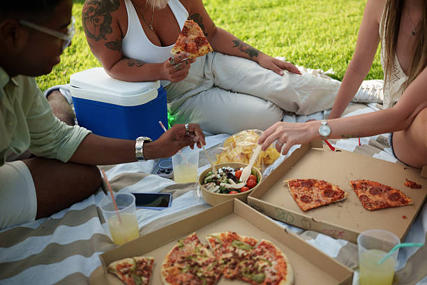 Friends eating pizza and salad at a picnic
