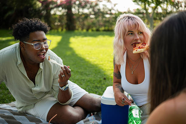 Two cheerful beautiful women friends having a picnic in a park. Hobbies, relaxation and outdoor activities concept.