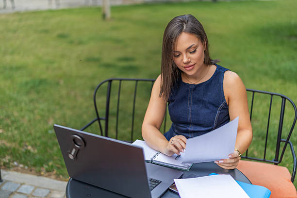 istock Young woman analyzing financial documents at desk with laptop while working in home office, focusing on tasks in an organized and productive environment. 2225275966