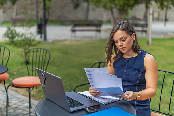 istock Young woman analyzing financial documents at desk with laptop while working in home office, focusing on tasks in an organized and productive environment. 2225275980