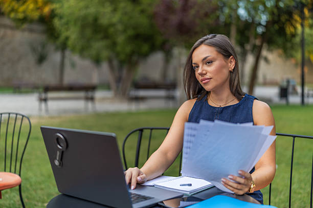 istock Young woman analyzing financial documents at desk with laptop while working in home office, focusing on tasks in an organized and productive environment. 2225276024
