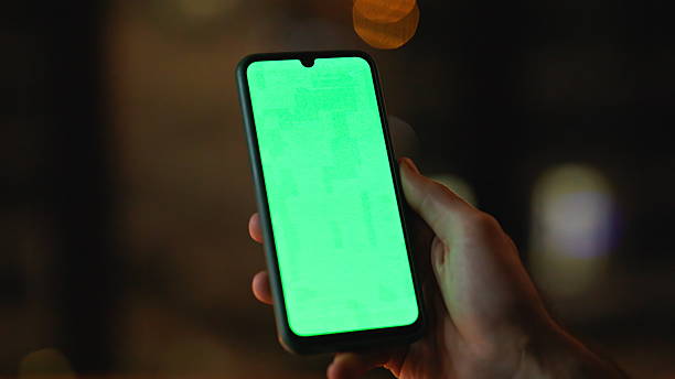 istock Guy hand holding green screen smartphone at night apartment closeup. Unknown man 2225278377