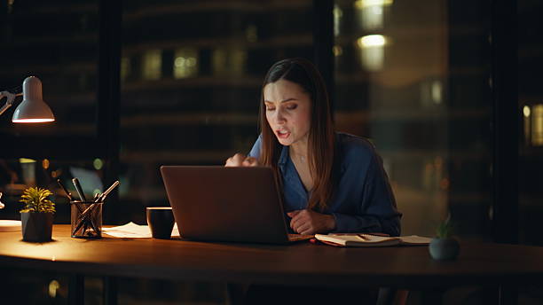 istock Woman boss arguing virtual conference showing papers to webcam at night office. 2225278914