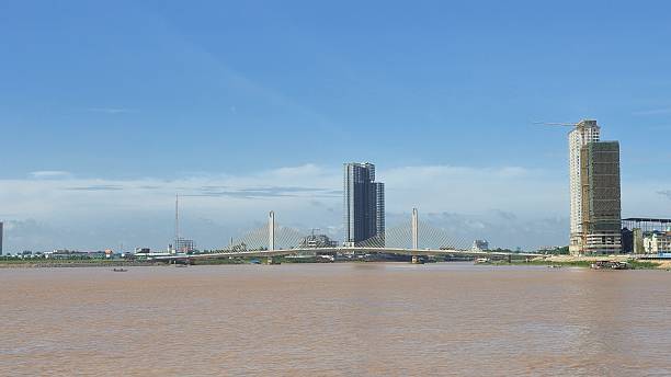 istock A modern cable-stayed bridge spans the Mekong River in Phnom Penh, flanked by high-rise buildings and a construction site under a clear blue sky. 2225279720