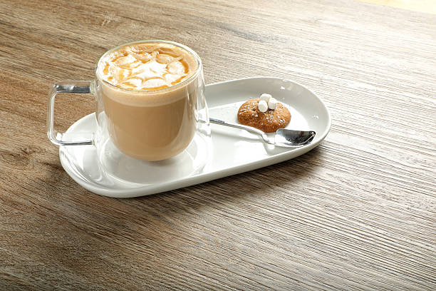 Glass cup of cappuccino and cookie on wooden table