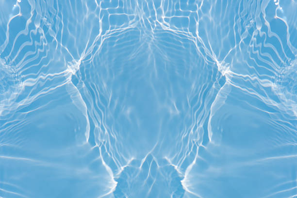 Blue water with ripples on the surface. Defocus blurred transparent blue colored clear calm water surface texture with splashes and bubbles. Water waves with shining pattern texture background.