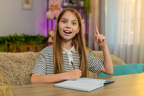 istock Child girl kid doing school homework at table happily solving problem excited expression at home 2225282744