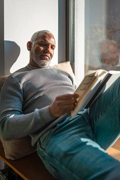 istock Mature Hispanic Male Reading by Sunlit Window 2225283939