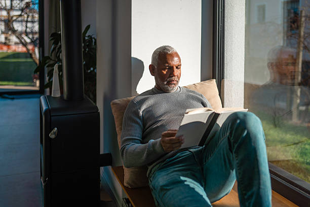 istock Mature Hispanic Male Reading by Sunlit Window Indoors 2225283940