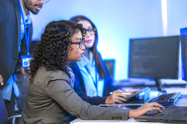 istock Diverse team of AI developers collaborating in a modern office. Indian male leading a discussion with Asian and Hispanic female colleagues on a machine learning project. 2225284595