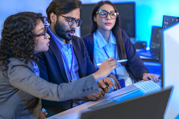 istock Diverse team of AI developers collaborating in a modern office. Indian male leading a discussion with Asian and Hispanic female colleagues on a machine learning project. 2225284738