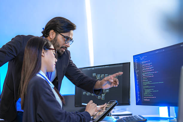 istock Asian female AI programmer and Indian male data analyst reviewing code on a monitor. Diverse tech professionals collaborating on an artificial intelligence project in a modern office. 2225285682