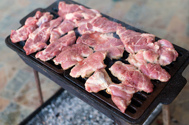 Red raw pork meat roasted on barbecue grill in summer.